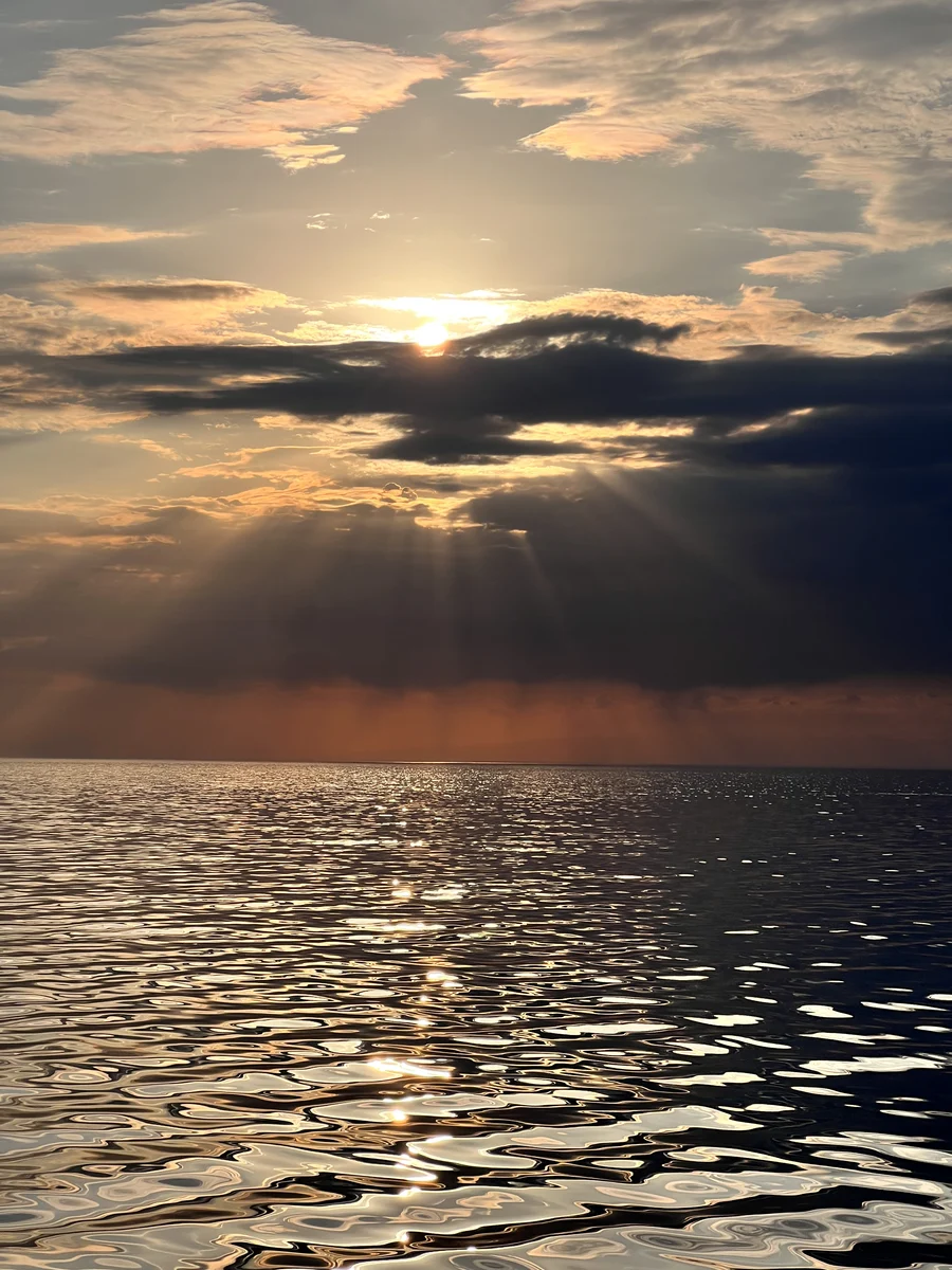 Sun rays breaking through clouds over the rippled waters of Issyk-Kul Lake at sunset
